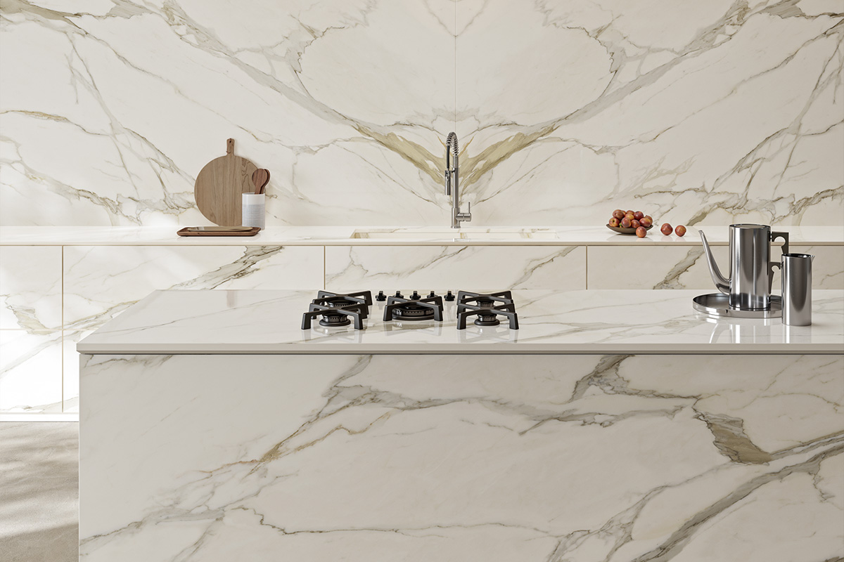 Cucina moderna con top e backsplash in grès porcellanato effetto marmo bianco Optimum Calacatta Gold, venature oro su fondo avorio, abbinata a basi in pietra chiara, stile Japandi